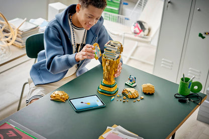 LEGO FIFA World Cup trophy brick model on a table while a child builds nearby