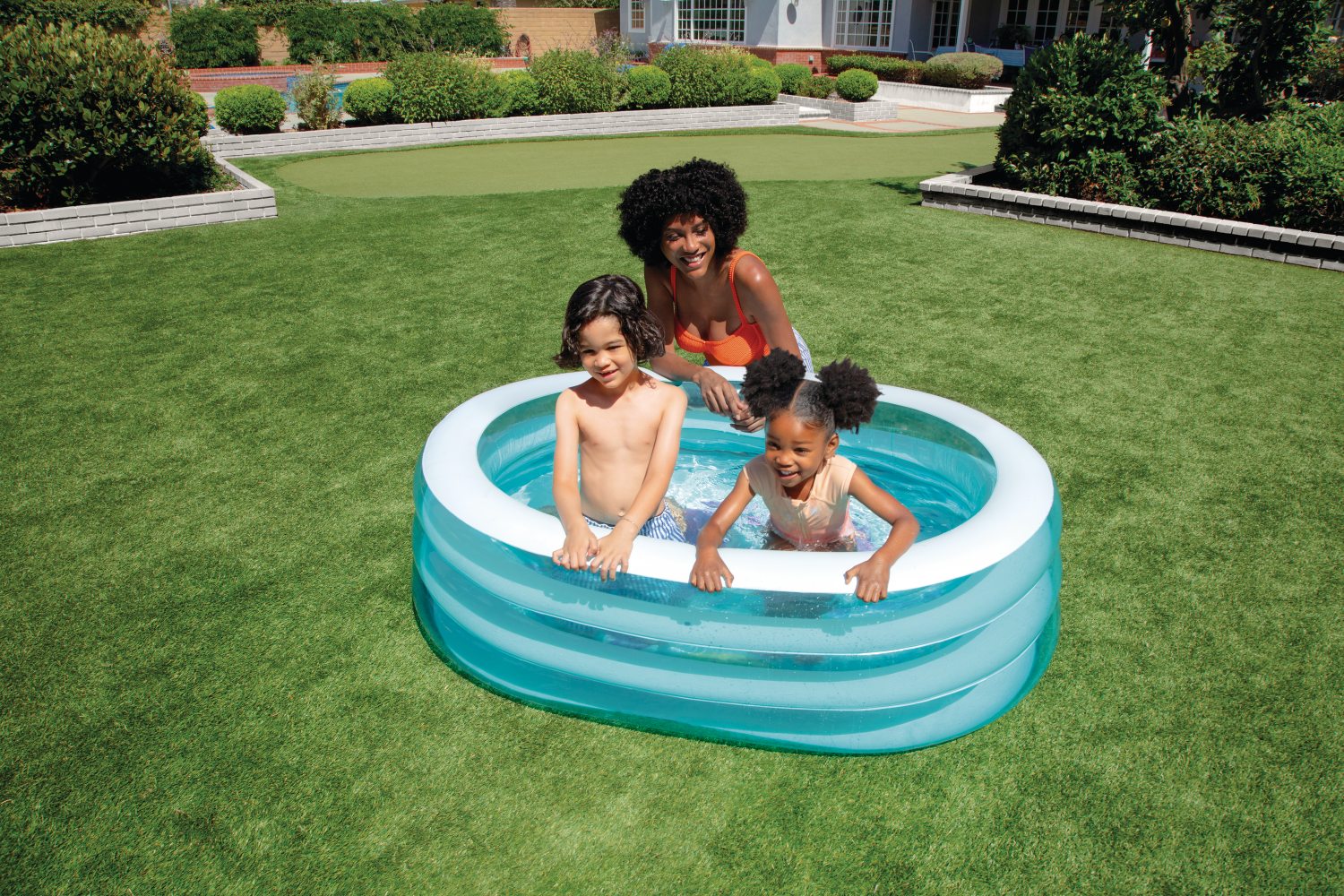 Inflatable sea-themed kids pool in backyard, with children playing in the water