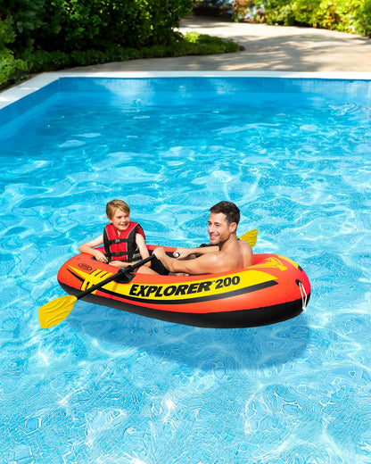 Inflatable orange boat floating in pool with yellow paddles and black oar handles