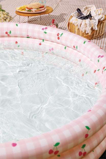 Inflatable kiddie pool with cherry-patterned pink gingham rim, clear water inside