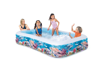 Inflatable rectangular pool with sea-life print sides and white rim, children playing in water