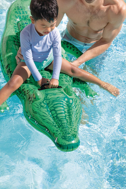 Green inflatable alligator ride-on in pool, with child seated and adult holding