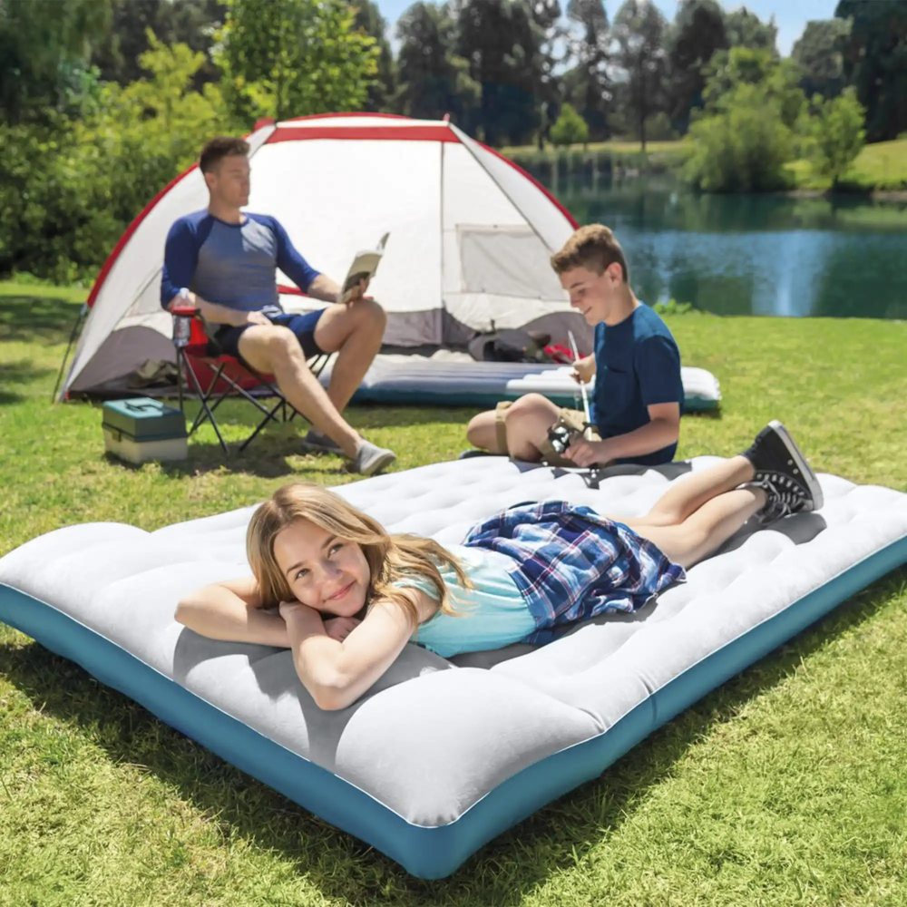 Camping air mattress on grass with gray top and blue edges
