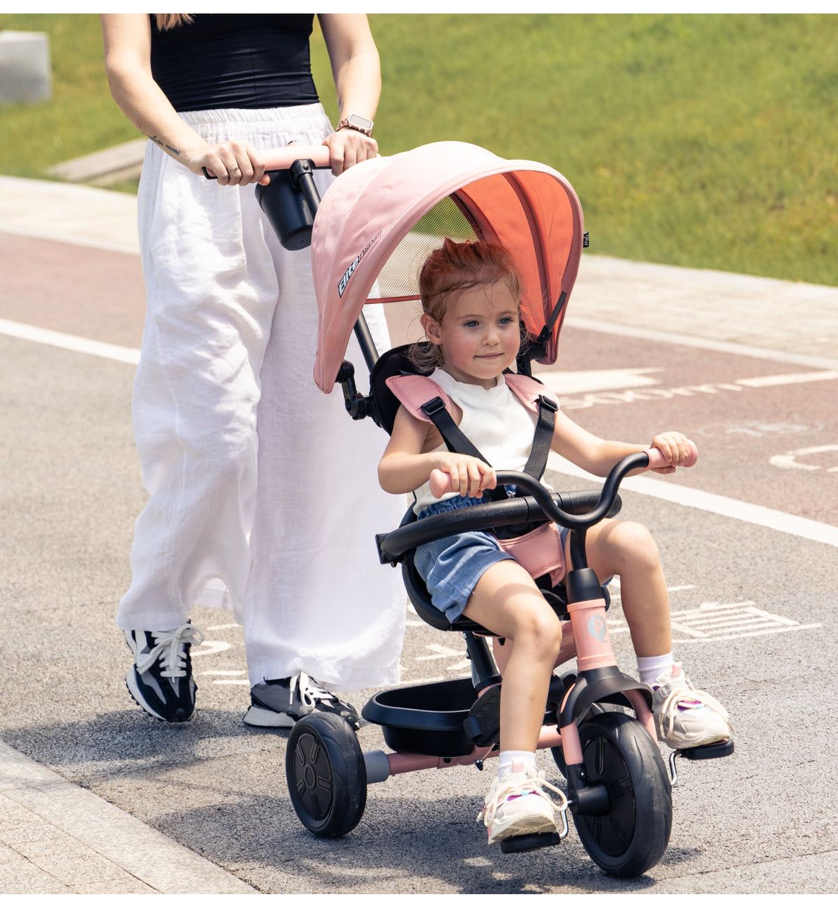 Green 3-wheel stroller trike with canopy, footrest, and child seated