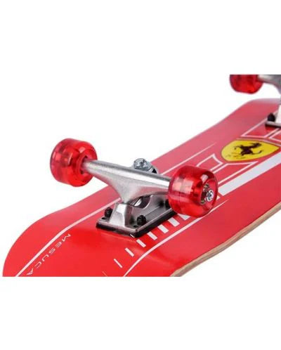 Ferrari skateboard front truck close-up with red wheels and yellow shield on red deck