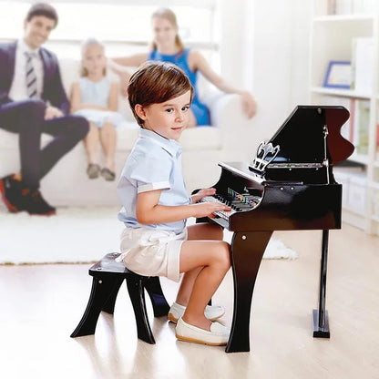 Kinder sitzt am schwarzen Klavier; Tastatur und Deckel offen sichtbar