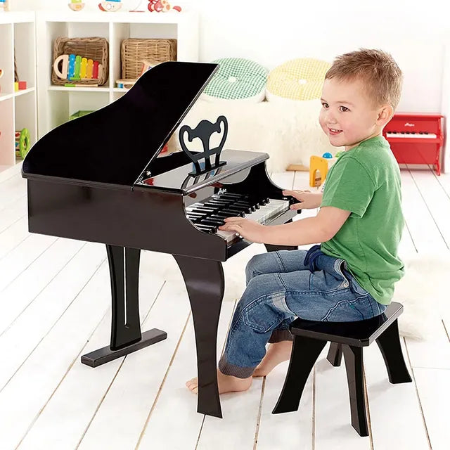 Schwarzes Kinderklavier mit geöffnetem Deckel, Kind spielt am Sitzhocker