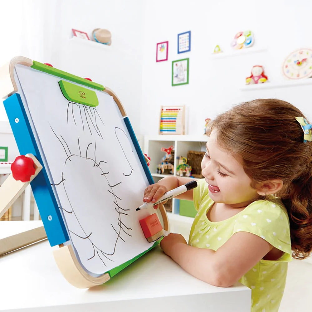 ANYWHERE ART STUDIO Zeichenbrett auf Ständer, Kind zeichnet mit Stift; Zubehör liegt am Brett