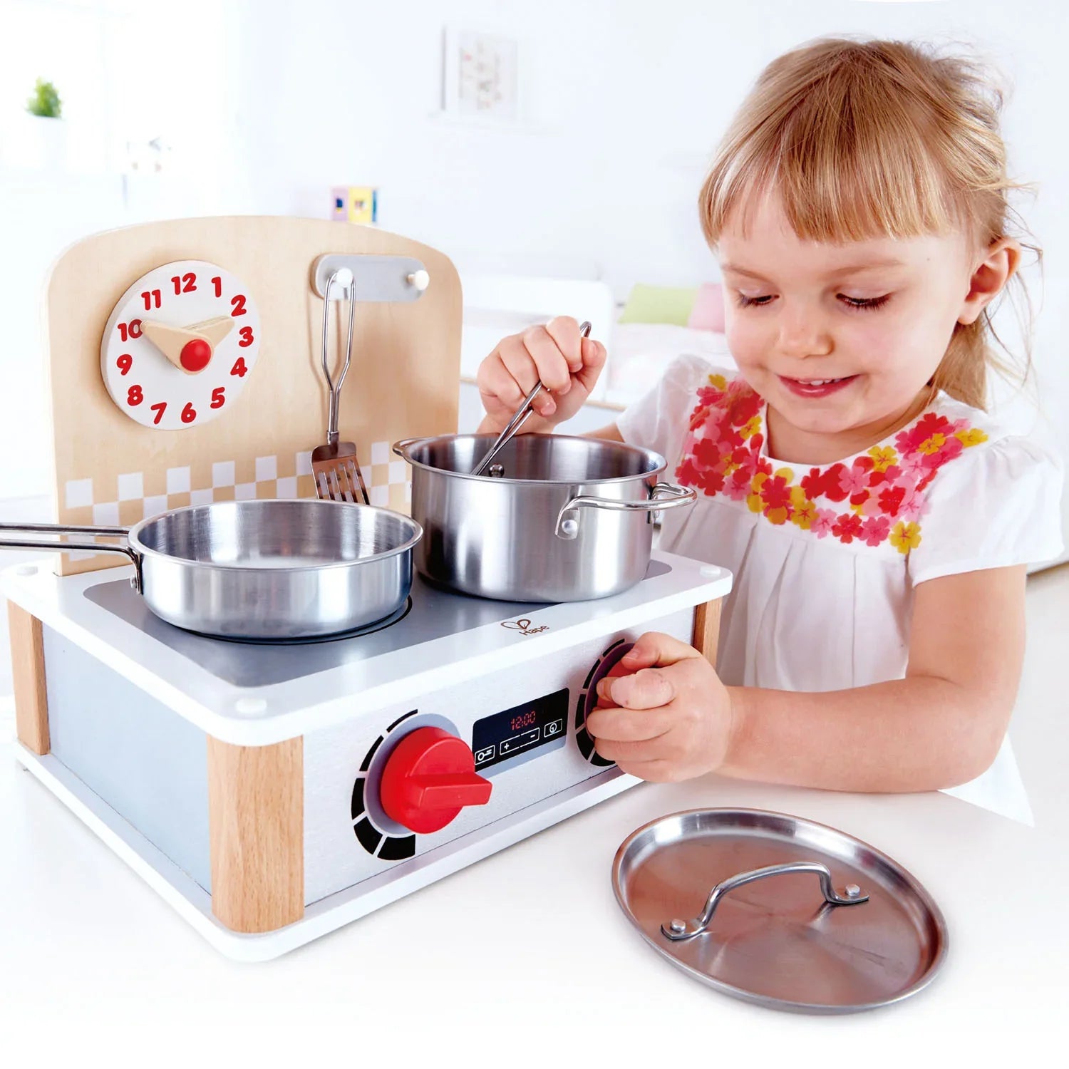 Toy stove with clock panel, two metal pots, red control knobs