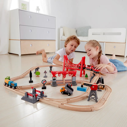 Curved wooden railway with red overhead bridge, signals, trucks and toy trains