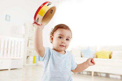 TAP-ALONG TAMBOURINE am Griff: Kind hält ein rotes Rahmentamburin mit Metallklappern