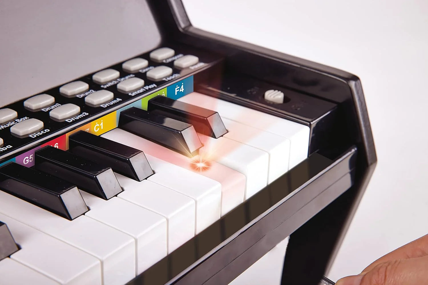 Toy keyboard close-up with white keys and colored label buttons on dark panel