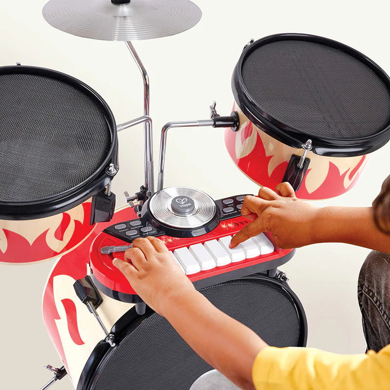 Red flame drum set close-up with mesh pads, keyboard panel, and drumsticks