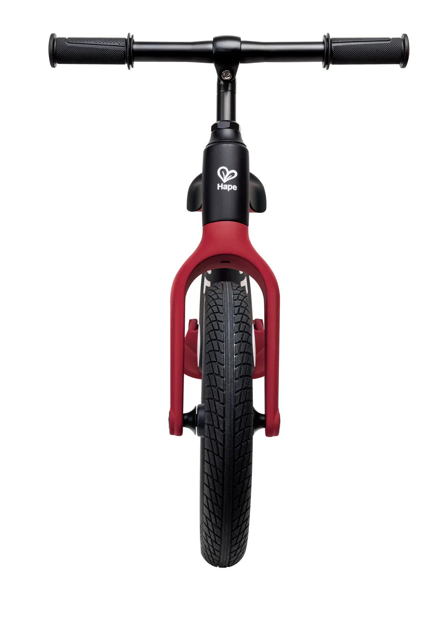 Black front fork and handlebars with red frame on a learner balance bike