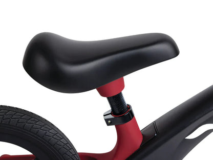 Black seat with red post and black handlebar on a red learner balance bike