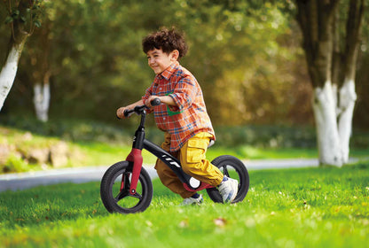 Child riding a red and black learner balance bike with large tread tires