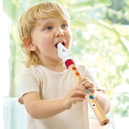 Child holding Hape recorder with colored finger holes, wooden body, white/red top