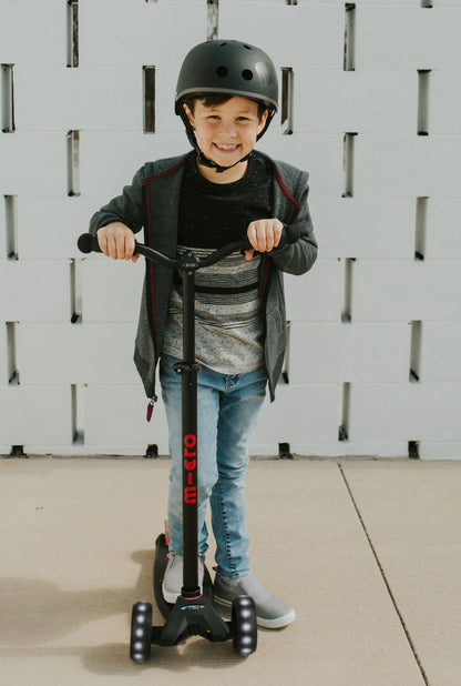 Child standing behind a dark LED scooter with handlebars and front wheels