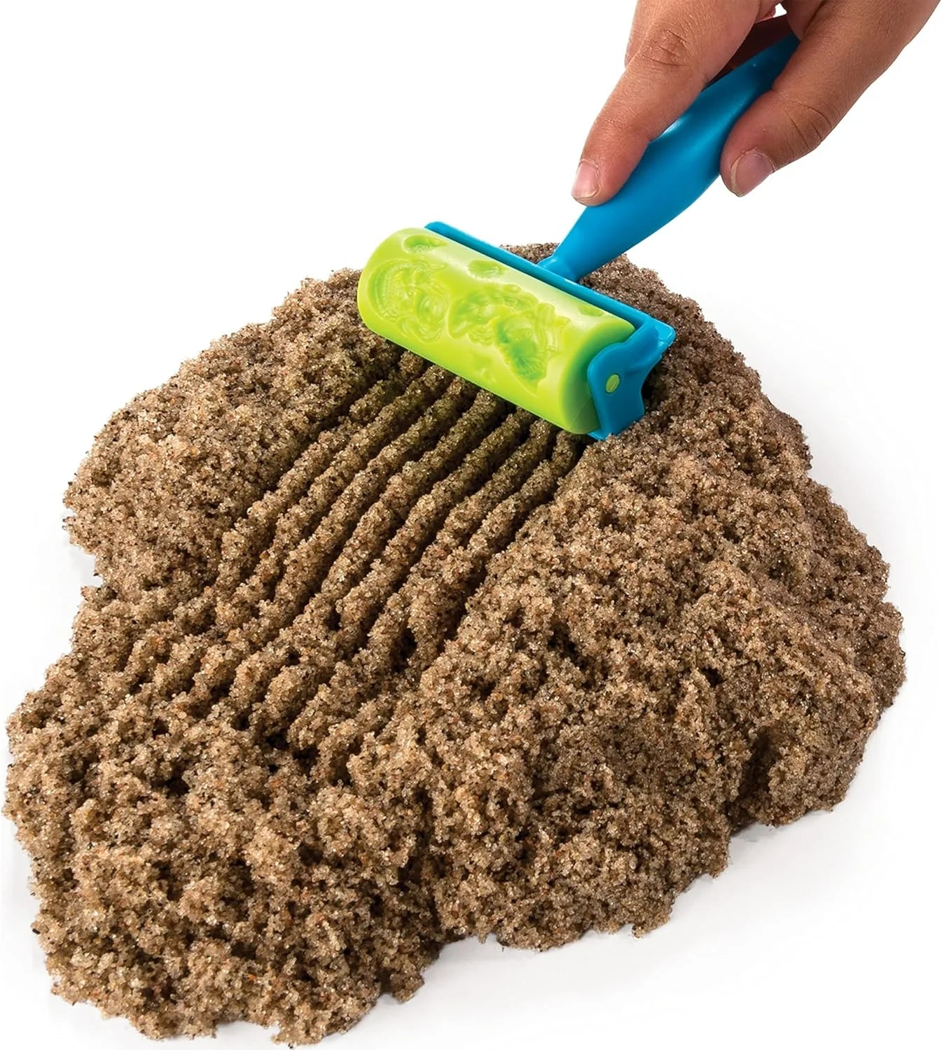 Hand using blue-and-green roller tool on brown kinetic sand