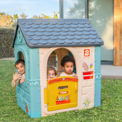 Blue and white kids playhouse with gray shingle roof and yellow activity door