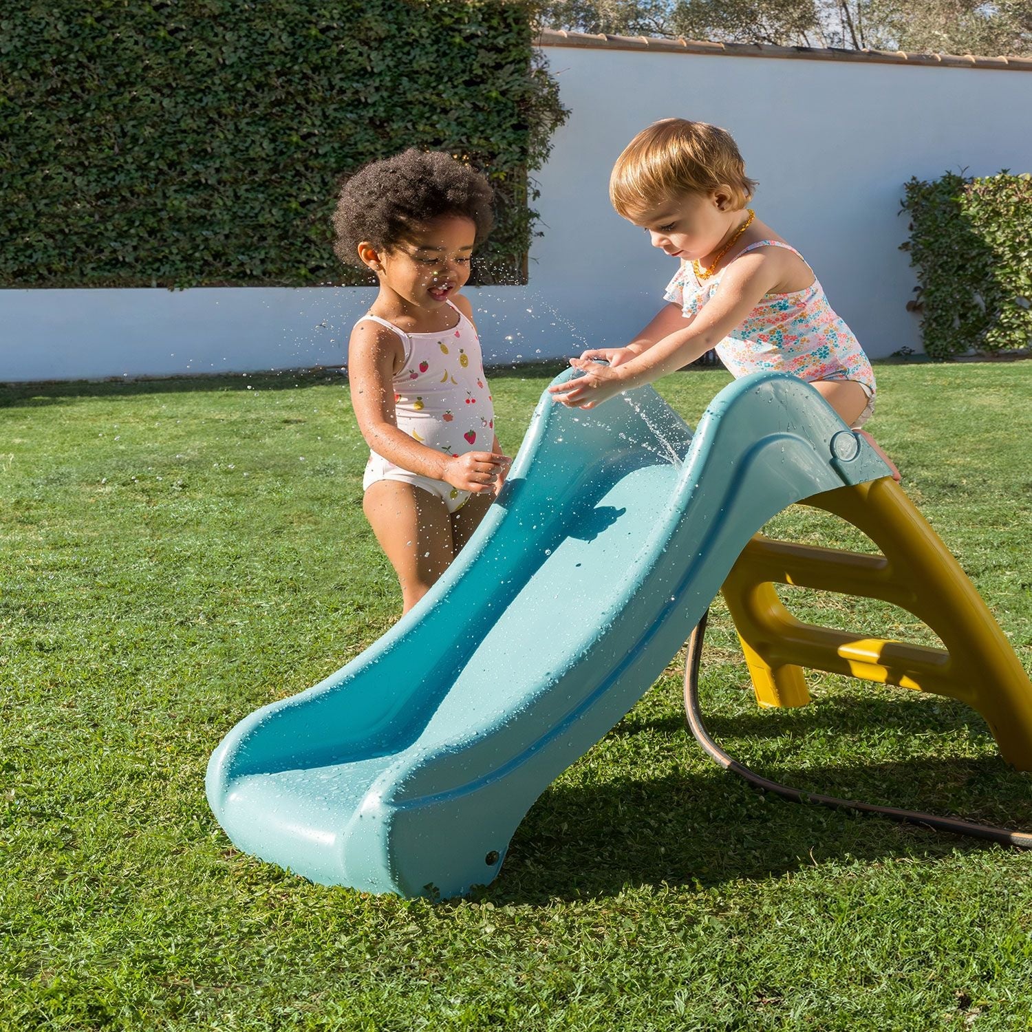 Blue playground slide with yellow ladder, shown with water on the chute