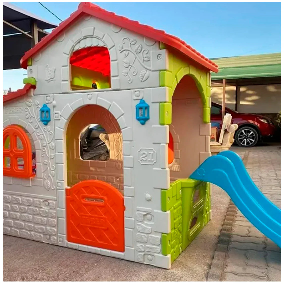Colorful plastic playhouse close-up with blue slide, red roof, arched door