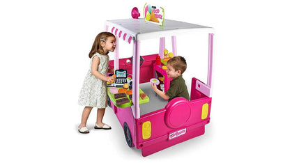 Pink toy food truck playhouse with kids using the front window and play kitchen panel
