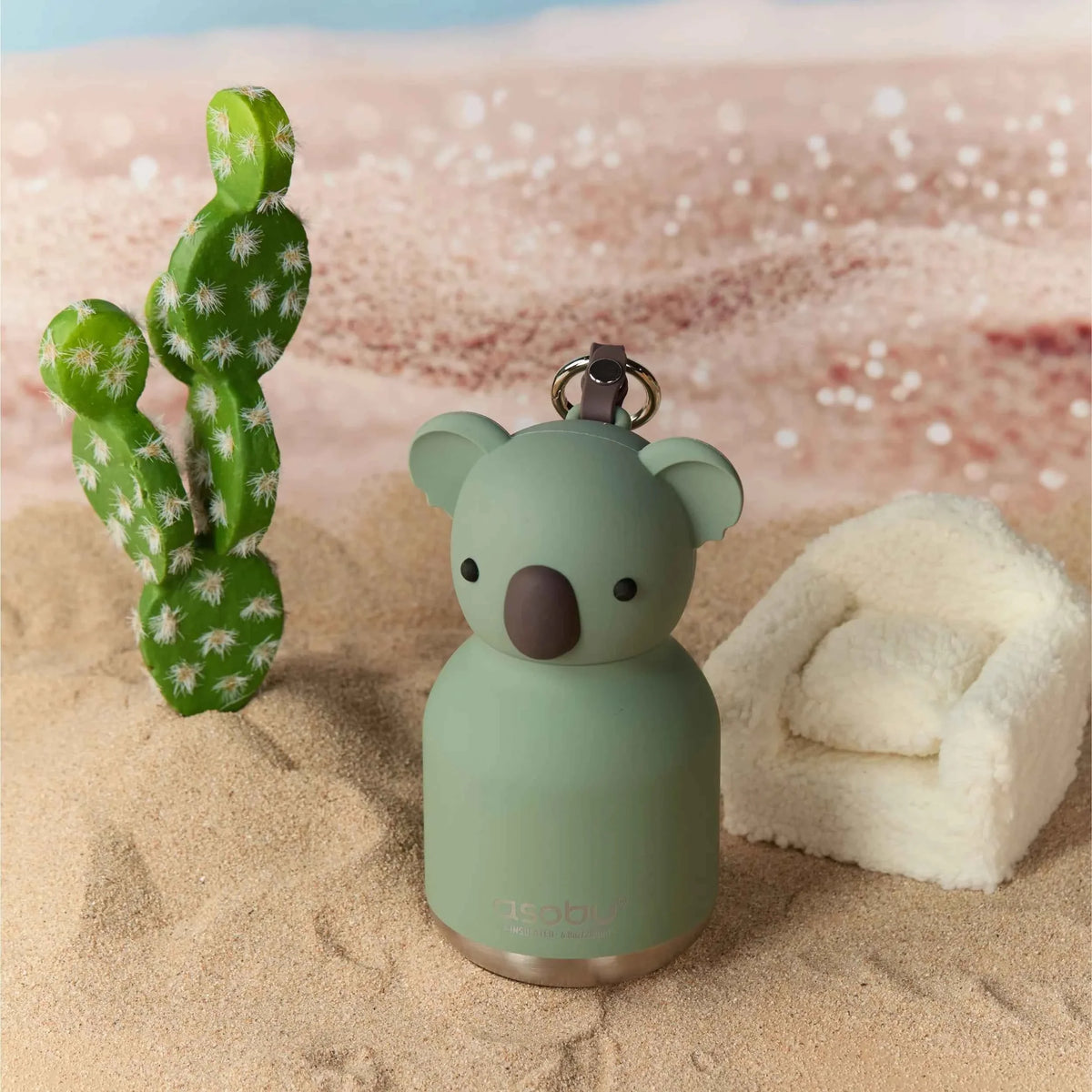 Koala-shaped mini water bottle on sand with mint body and metal key ring.