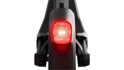 Rear light of dark electric e-scooter glowing red