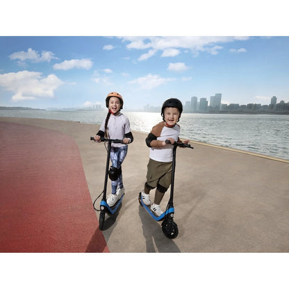 Two kids riding blue kick scooters with black wheels on a waterfront walkway