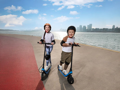 Child on a blue kick scooter with black handlebars and wheels beside water