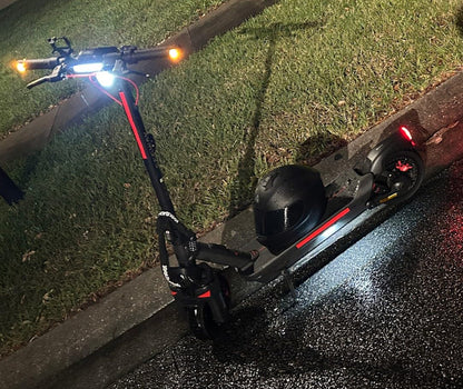 Electric kick scooter with illuminated lights and textured deck, angled on pavement