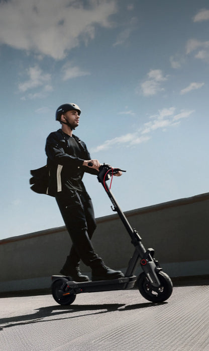 Electric kick scooter being ridden, handlebar and front wheel in side profile