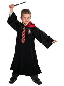 Child in black robe with red-and-gold striped tie, holding a wand