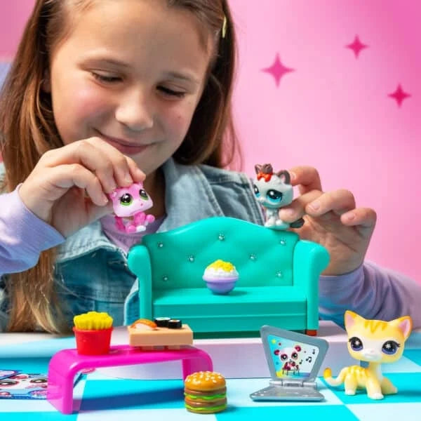 Diner Dash play set with a girl playing beside teal sofa, cat figures, and laptop accessory