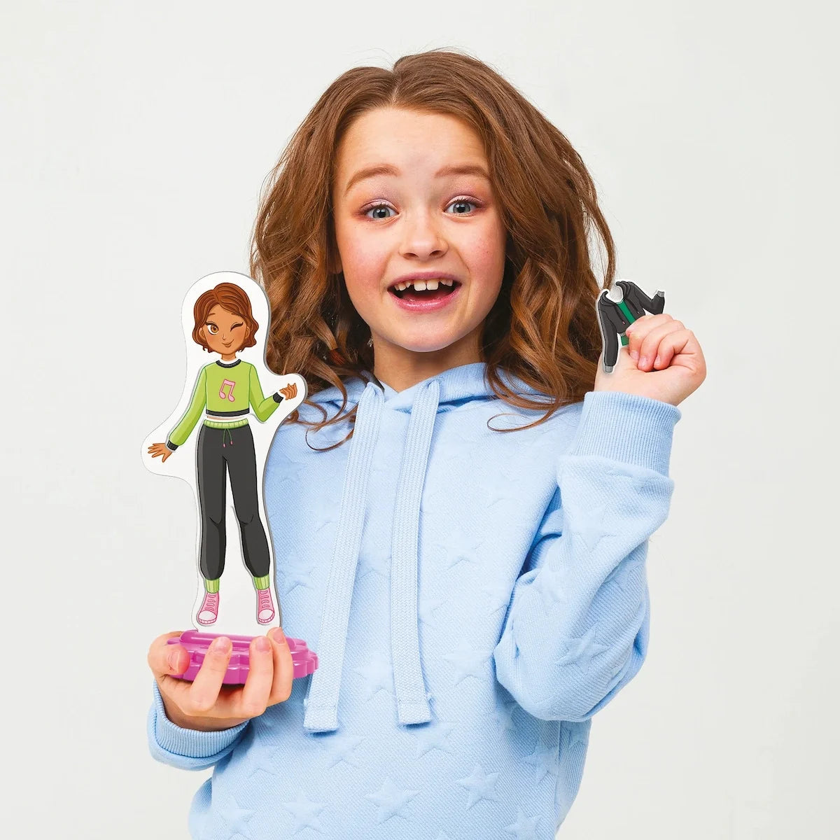 Magnetic dress-up play set pieces held by child, including girl cutouts and dresses