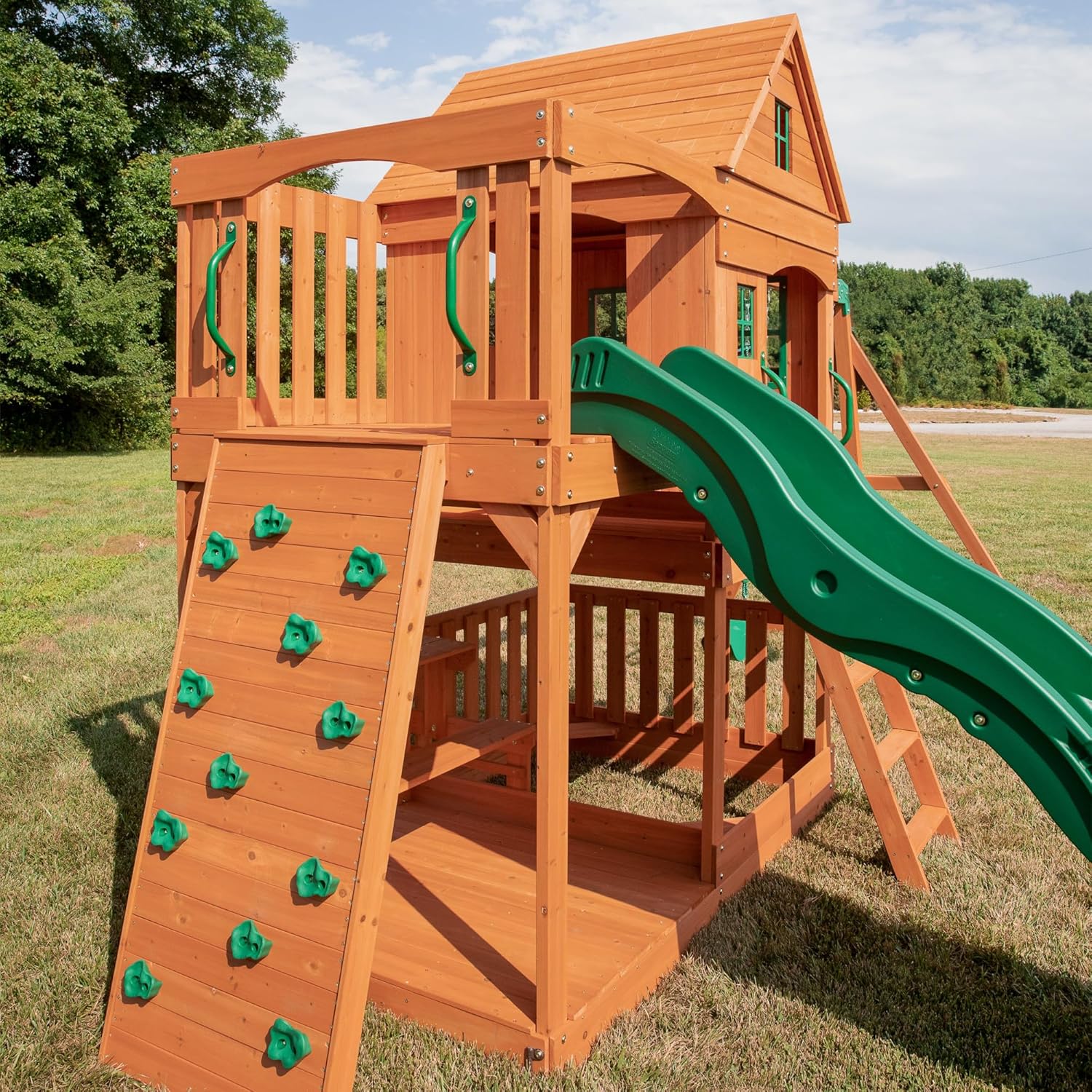 Holz-Spielturm mit Kletterwand, grünem Rutschenteil und Plattform mit Geländer