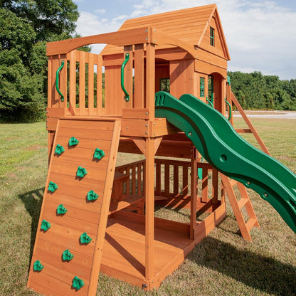 Holz-Spielturm mit Kletterwand, grünem Rutschenteil und Plattform mit Geländer