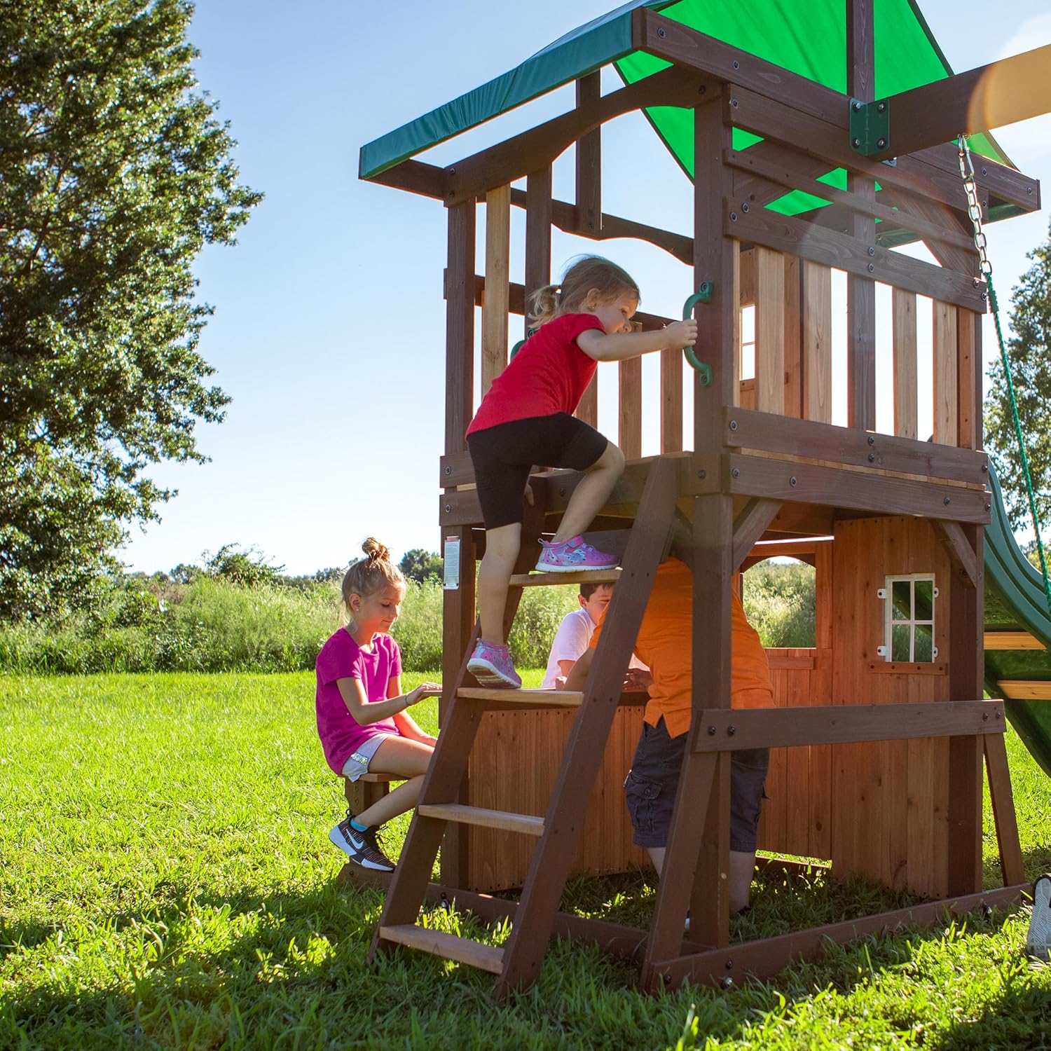 Wood playhouse tower with ladder and green canopy, kids climbing and playing