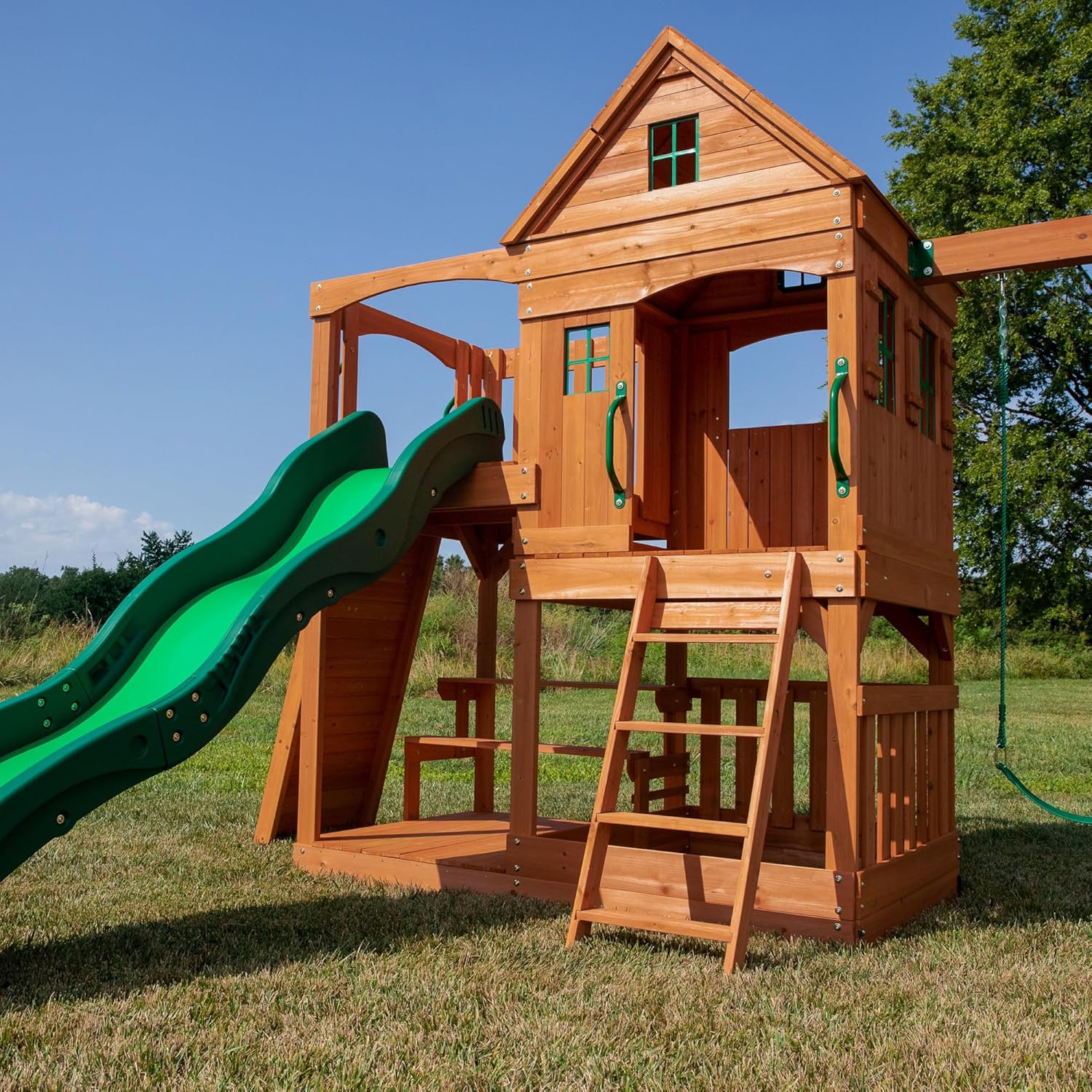Holz-Spielturm von der Seite mit Leiter, grünem Rutschenteil und Schaukelaufhängung