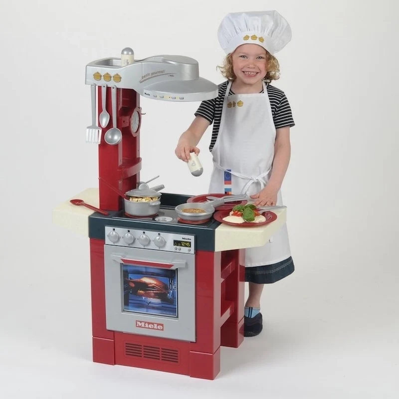 Kids kitchen set in red and white with oven window; shown with chef hat child