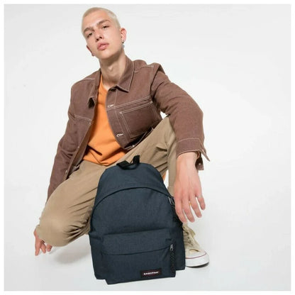 Denim backpack worn crossbody, dark blue with EASTPAK patch and side zippers
