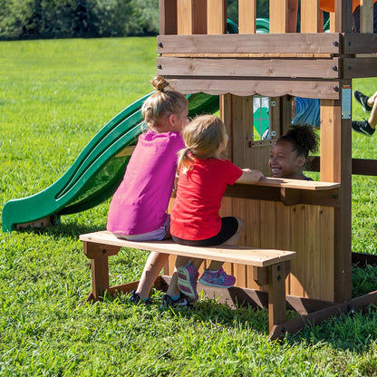 Green slide and covered playhouse bench area with open window on wooden wall