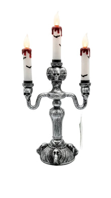 Three-candle skull candle stand with three white candles and red wax drips