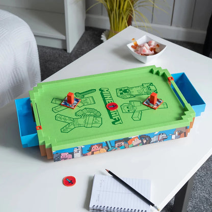 Desktop air hockey rink with green surface, red puck, and character-style pushers