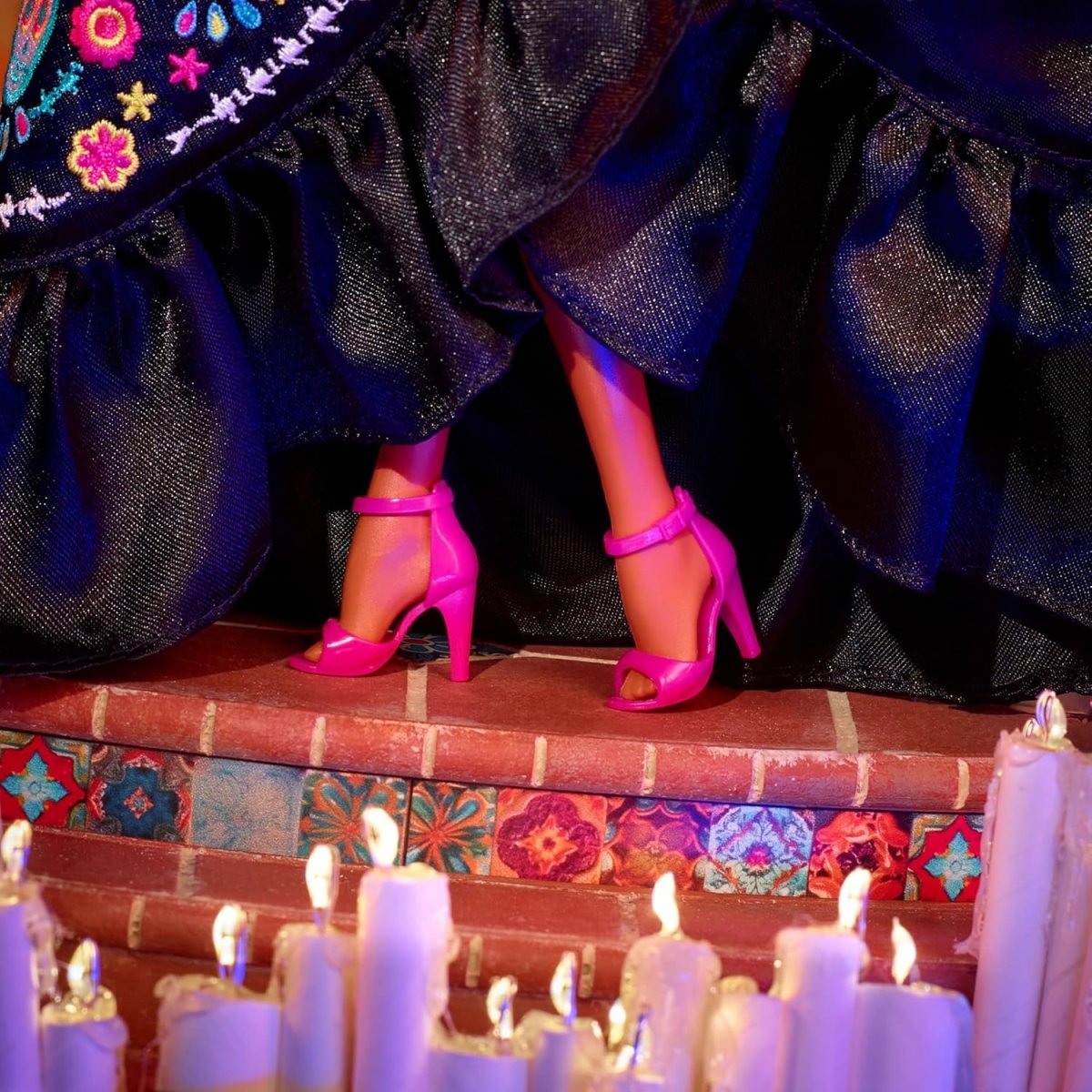 Vista de piernas de la muñeca: zapatos de tacón fucsia y dobladillo del vestido negro con brillo.