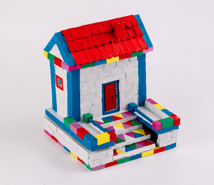 Brick house model with blue walls, red roof, colorful accents, and patio base