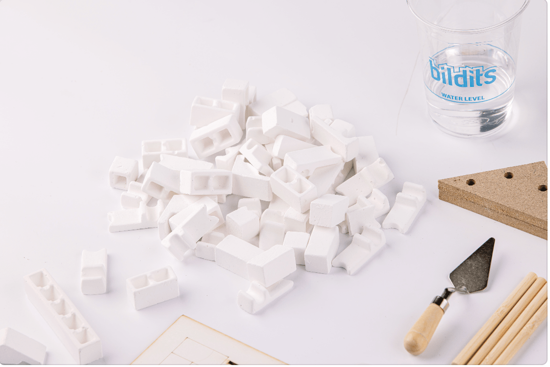 Building set pieces: white blocks, triangle tool, wooden rods, and water level cup