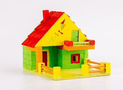 Painted cottage dollhouse model with red-and-yellow roof, green walls and picket fence