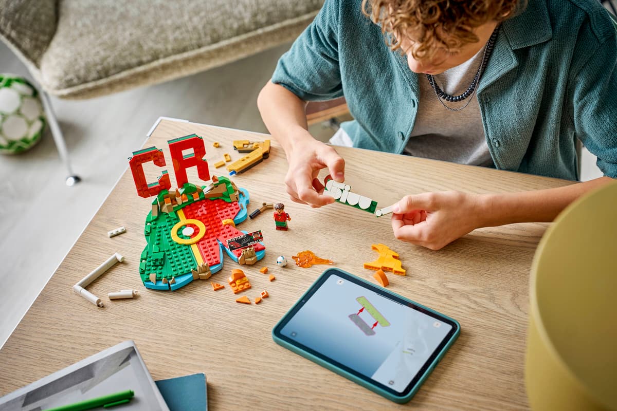 Person fitting LEGO pieces on a tabletop while assembling the CR7 soccer highlights build